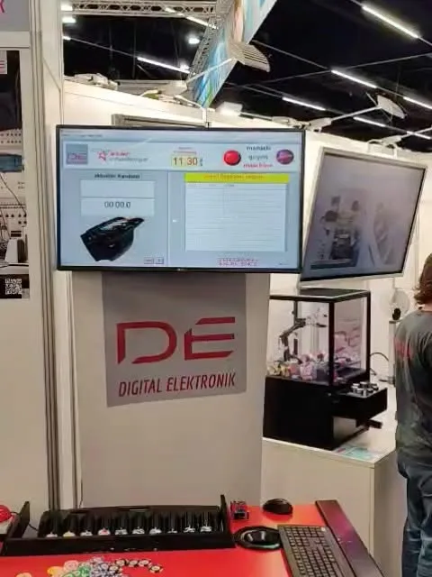 Messestand mit zwei Bildschirmen, einer Vitrine und dem DE-Logo am Pult