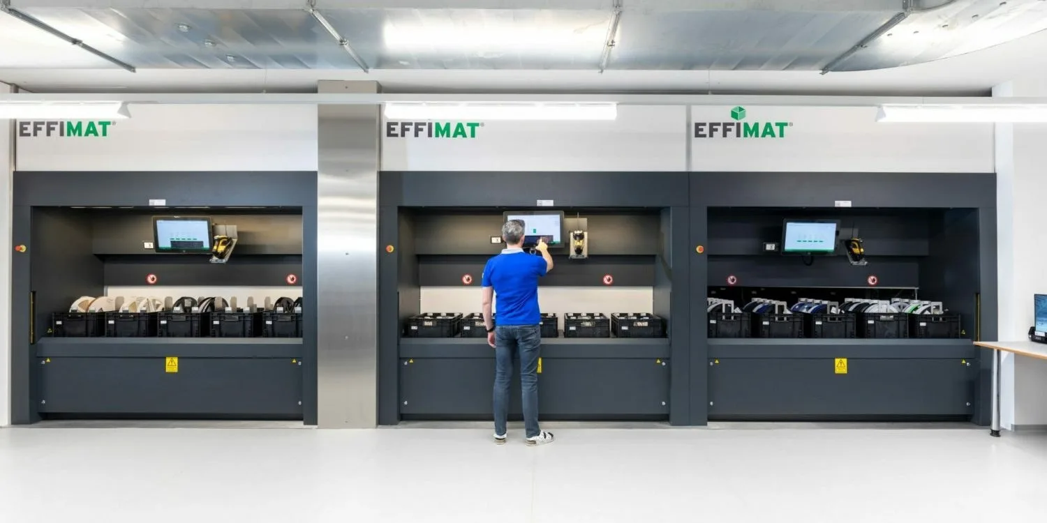 Mitarbeiter an der Bedienstation eines automatisierten Lagersystems mit drei Ausgabeöffnungen